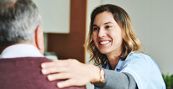 A woman with her hand on a man's shoulder, talking to him