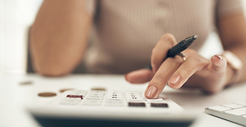 A close-up of a woman typing into a calculator