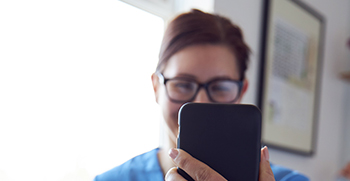 A close-up of a woman looking at her phone and smiling