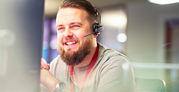 A patient attending a telehealth visit on his laptop while a transcriptionist takes notes offscreen