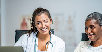 A doctor and her patient looking at a laptop together