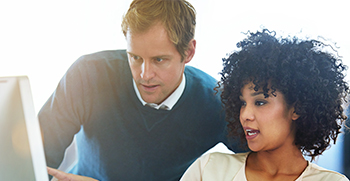 A man and a woman looking at a computer together and talking